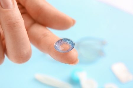 Female,Hand,With,Contact,Lens,On,Color,Background